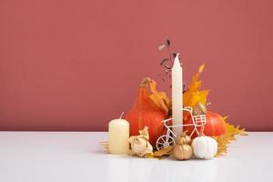 Autumn composition. Dried leaves, pumpkins and candles on white pink background. Autumn fall and thanksgiving day concept. Still life photo