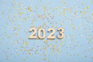 números de madera 2023 sobre un fondo azul pastel con estrellas. fondo festivo de año nuevo foto