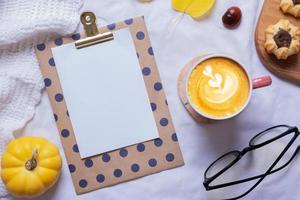 hoja de papel en blanco y taza de café con leche con vista superior de decoración acogedora de otoño. copie el espacio para el texto de otoño foto