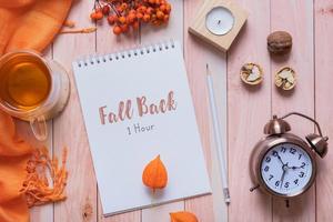 Time Change concept with autumn cozy decor top view on desktop with alarm clock and laptop. Fall back concept. photo