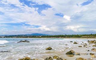 Beautiful surfer waves rocks cliffs at beach Puerto Escondido Mexico. photo