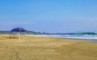 Purple parasol in the wind at  beach Puerto Escondido Mexico. photo