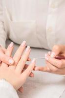 Woman receiving french manicure by beautician photo