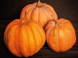 Three ripe orange pumpkins on a black background. Harvest, pumpkins. photo