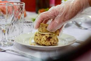 Table setting in a cafe. Bag of pancakes with filling on a plate. photo