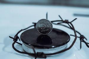 Restrictions causing shortages in gas supplies, burners Gas stove with barbed Wire and ruble coin, concept gas crisis photo