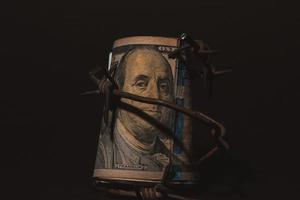 billete de dólar con alambre de púas, crisis económica, efecto de fondo con poco ruido foto