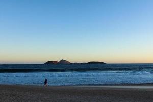 Rio de Janeiro, RJ, Brazil, 2022 - Ipanema at sunset, people walking on the beach in silhouette photo