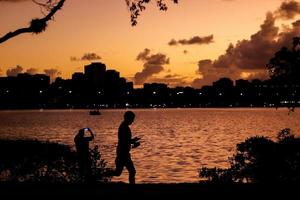 Rio de Janeiro, RJ, Brazil, 2022 - People running and biking in silhouette at sunset at Rodrigo de Freitas Lagoon photo