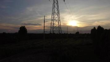 Aerial view of high voltage pylons and wires in the sky at sunset in the countryside. Drone footage of electric poles and wires at dusk. video