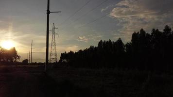 vista aérea de torres de alta tensión y cables en el cielo al atardecer en el campo. imágenes de drones de postes eléctricos y cables al atardecer. video