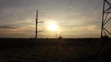 vue aérienne des pylônes et des fils à haute tension dans le ciel au coucher du soleil dans la campagne. images de drones de poteaux électriques et de fils au crépuscule. video