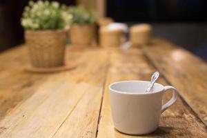 taza de café caliente arte latte con cuchara servir listo para beber en la cafetería en la cafetería de mesa de madera. deje el espacio de copia vacío para escribir el texto lateral. enfoque suave. foto