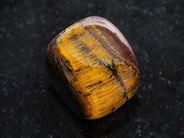 polished tiger-eye gem stone on dark background photo