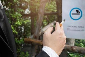 los hombres de negocios fuman cigarrillos sentados en el parque en el área de la zona de fumadores. foto