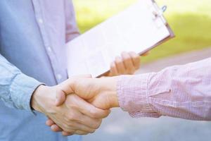 Close up of a business man hand shake between two colleagues greet, Document file sign contract agreement business success, Represents Friendship is good,success, congratulations. photo