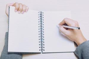 close up hand woman are writing notepad down cost into the book sit on the sofa. photo