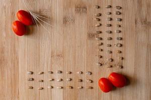 Red cherry tomatoes with sunflower seeds on wooden background photo