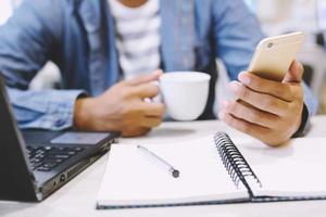 close up writer hand person people sit in coffee shop are writing notepad down write down the story into the book on table And use the phone to record sounds placed beside the coffee cup. photo