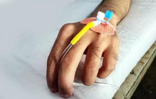 Patient's left hand with saline intravenous dripping in the hospital photo