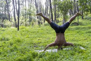 hombre latinoamericano haciendo postura de yoga, postura de yoga, abeja al revés prsthatah brahmara, bosque foto