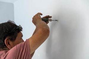 hombre desenroscando un tornillo con un destornillador manual o manual, hombre mayor, latino hispano foto