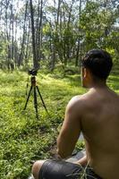 Millennial guy meditating with trainer online via tablet ipad connection, in the forest, broadcasting online your class and instructions, mexico photo