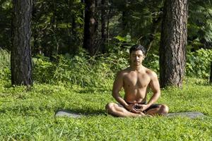 hispanic and latin man, meditating in the middle of a forest, receiving sun rays, brown skin, mexico photo