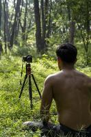 Millennial guy meditating with trainer online via tablet ipad connection, in the forest, broadcasting online your class and instructions, mexico photo