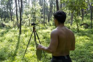 Mature middle-aged athlete man standing in stand position in sporty clothes on fitness mat, watching video training tutorial online, vlogging photo