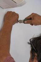 man unscrewing a screw with a hand or manual screwdriver, older man, hispanic latino photo