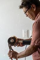 hombre usando amoladora angular, cortando un tornillo, chispas de fricción, tornillo de sujeción con pinzas cara de concentración y preocupación hombre latino foto
