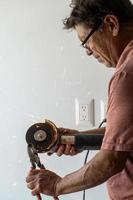 man using angle grinder, cutting a screw, friction sparks, clamping screw with tweezers concentration face and concern latino man photo