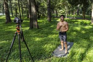 Active handsome male yogi walks in a park strolling forest before or after a workout. Young hispanic athletic man yoga class with a fitness mat photo