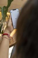 imagen de maqueta de una mujer sosteniendo y mostrando un teléfono móvil negro con pantalla en blanco foto