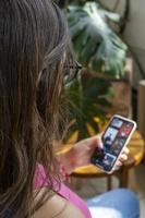 Happy millennial hispanic teen girl checking social media holding smartphone at home. photo