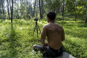 chico milenario meditando con un entrenador en línea a través de una conexión de tablet ipad, en el bosque, transmitiendo en línea tu clase e instrucciones, méxico foto