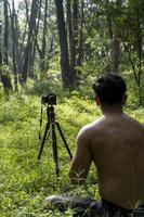 chico milenario meditando con un entrenador en línea a través de una conexión de tablet ipad, en el bosque, transmitiendo en línea tu clase e instrucciones, méxico foto