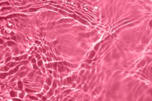 Defocus blurred transparent pink colored clear calm water surface texture with splash, bubble. Shining pink water ripple background. Surface of water in swimming pool. Pink bubble water shining. photo