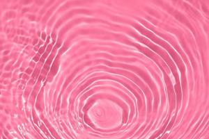 Defocus blurred transparent pink colored clear calm water surface texture with splash, bubble. Shining pink water ripple background. Surface of water in swimming pool. Pink bubble water shining. photo