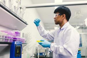 Asian male medical or scientific researcher or doctor using looking at a clear solution in a laboratory. photo