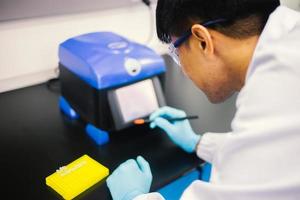 Asian male medical or scientific researcher or doctor using looking at a clear solution in a laboratory. photo