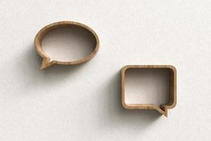 Wooden shelves in the shape of speech balloons on plaster wall. photo