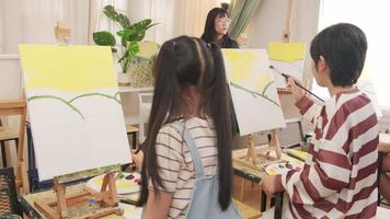 un groupe d'enfants asiatiques se concentre sur la peinture acrylique sur toile au pinceau dans une salle de classe d'art et apprend de manière créative avec talents et compétences à l'école primaire. video