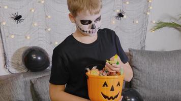 l'enfant sort les bonbons du seau pour halloween. le garçon célèbre le tour ou la friandise. video