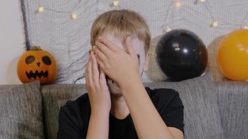 de jongen uitstrijkjes bedenken Aan zijn gezicht met zijn handen na de viering van halloween. op zoek Bij de camera