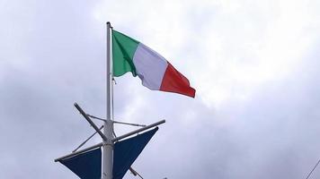 Italian flag flutters on the flagpole on a stationary ship on a dark cloudy background. video