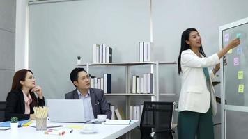 A group of businessmen sit in an office meeting and business women present their plans. video