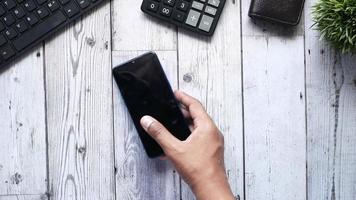 mão pega telefone inteligente da mesa com calculadora e teclado video