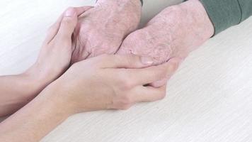 close-up de um homem mais velho segurando a mão. uma jovem cuida da saúde de seu avô. video